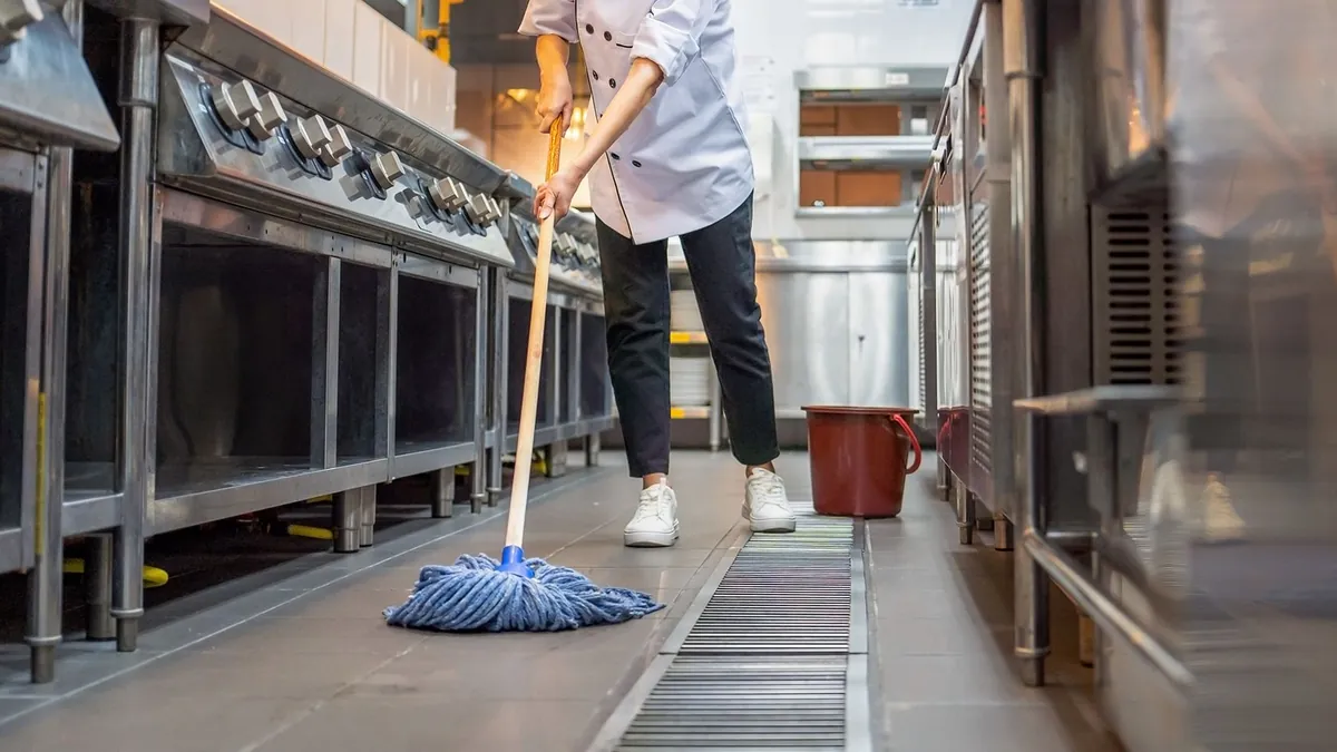 Worker degreasing a restaurant kitchen floor